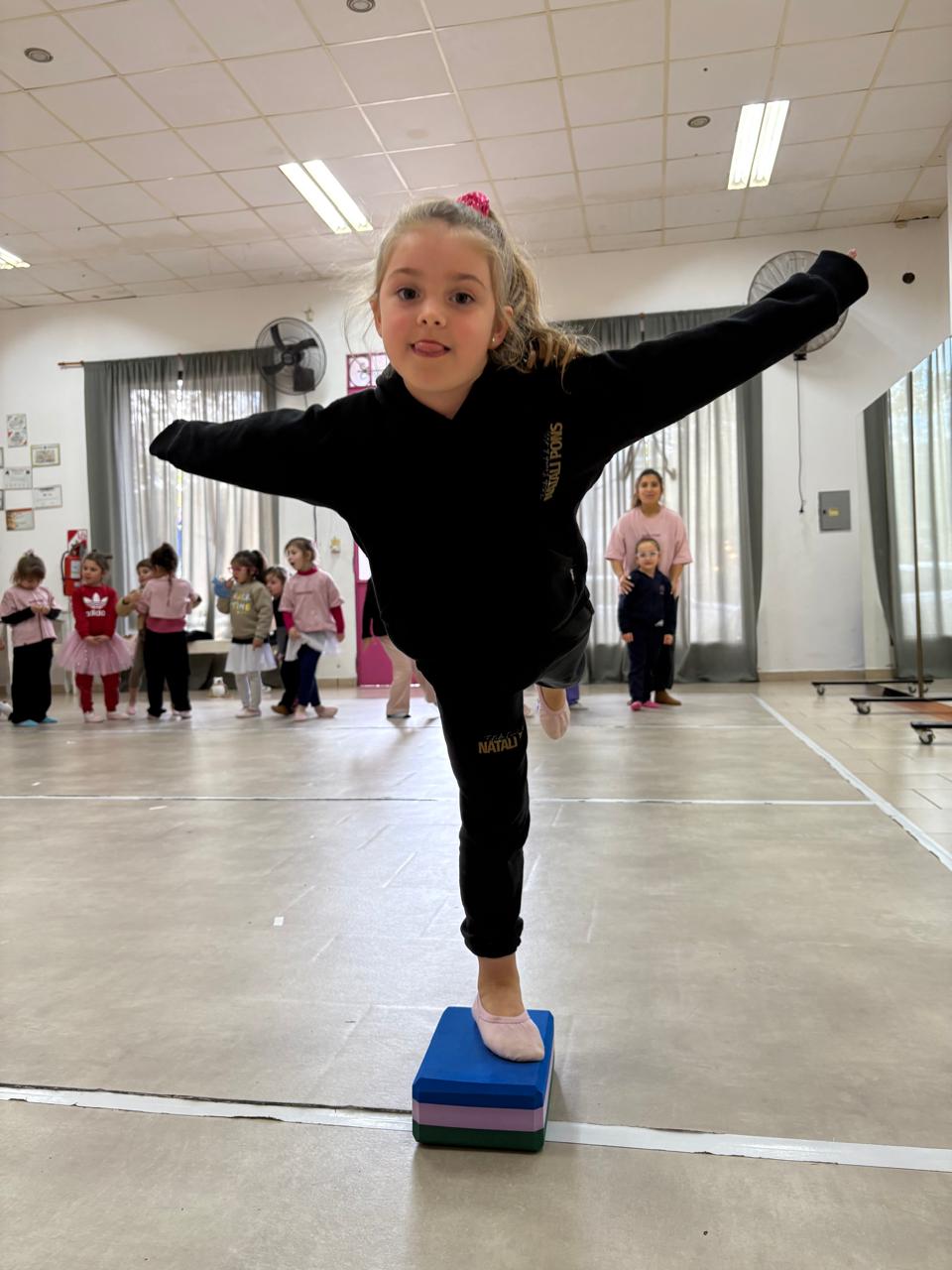 Niña en equilibrio sobre bloque de yoga